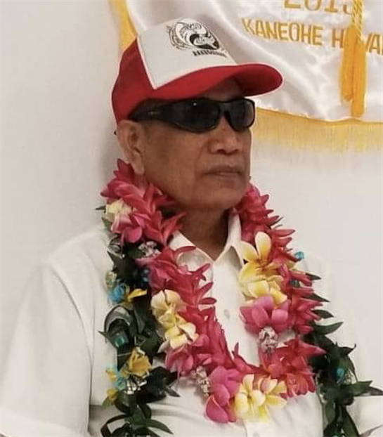 A community leader stands proudly adorned with a vibrant flower lei during a cultural ceremony.