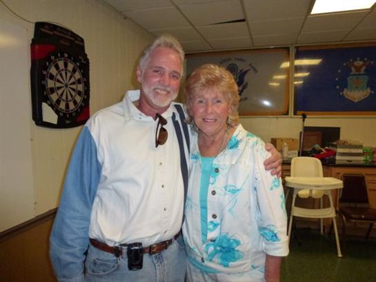 A smiling couple stands close, sharing joy at a community event in a lively atmosphere.