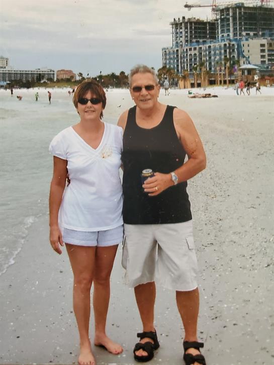 A couple smiles while standing on the shoreline, enjoying the warm sun and waves in Florida.