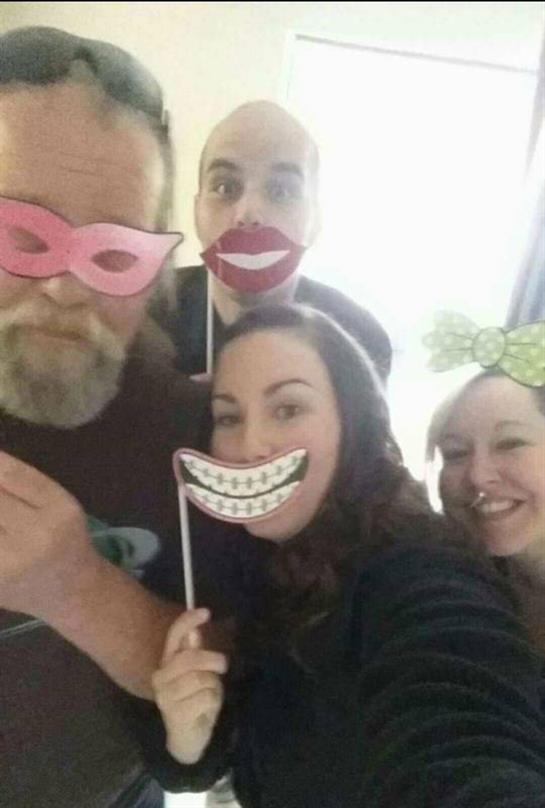 Four friends smile with playful props, enjoying each other's company.