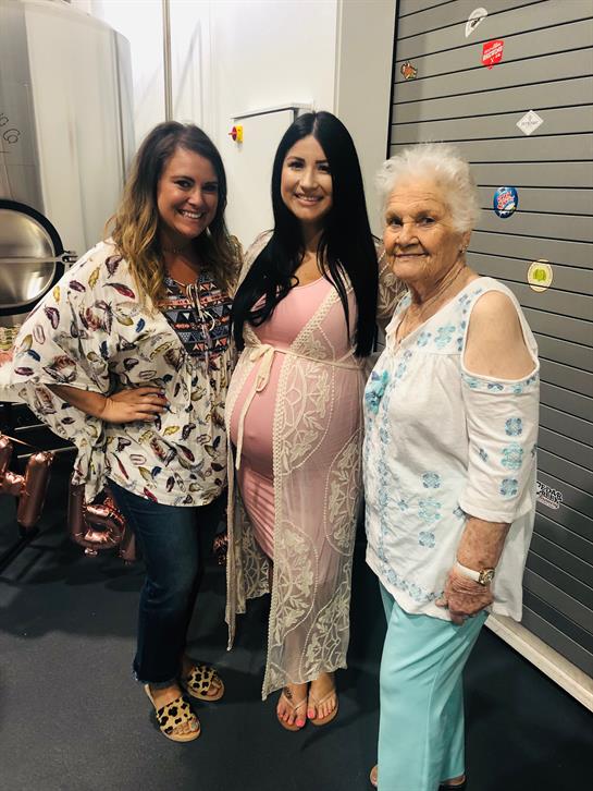 Three women share smiles at a celebration, highlighting joy and anticipation of new life.