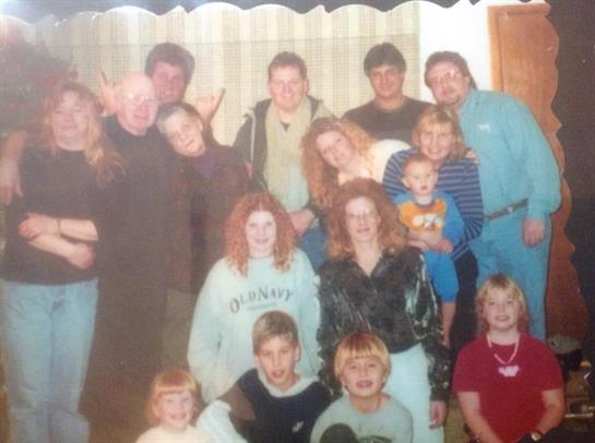 A group of people smiles and interacts in a cozy indoor space, showcasing family bonds.