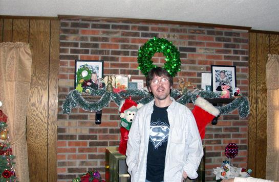 A man stands in a festive living room adorned with holiday decorations and a green wreath.