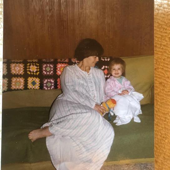 Grandmother and baby share a joyful moment on a couch in a comfortable living room environment.