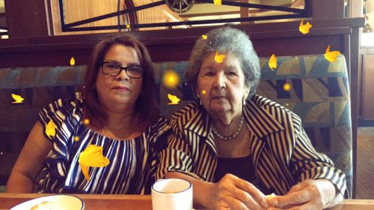 Two women sitting in a cafe, sharing a moment full of joy and warmth surrounded by butterflies.