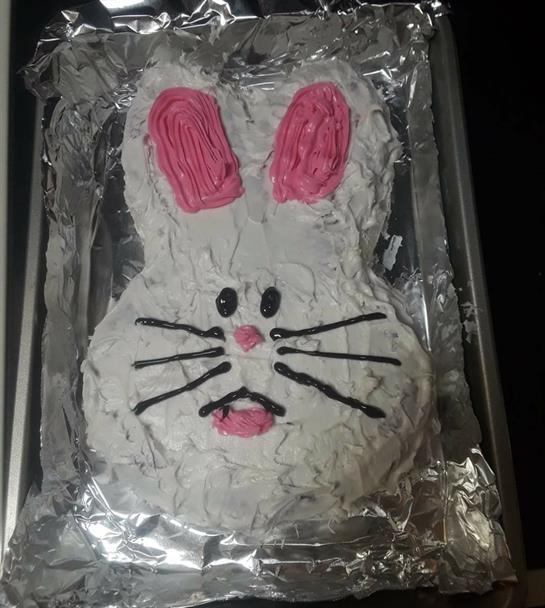 A whimsical rabbit cake with pink ears and black whiskers for a festive occasion.