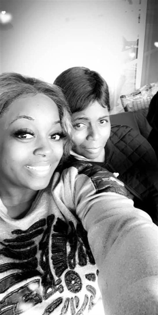 Two friends smiling together in a cozy, warmly lit living room.