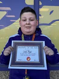 Young boy smiles while holding a certificate for achieving success in sports competition.