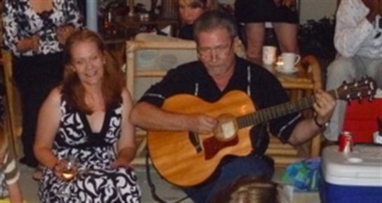 Guests engage at a lively event as a musician strums an acoustic guitar, creating a warm atmosphere.