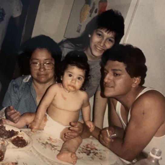 A happy family shares a meal while enjoying quality time with a baby in a cozy setting.