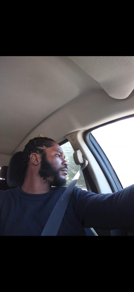 A man drives a vehicle, gazing thoughtfully out the window on a bright day.