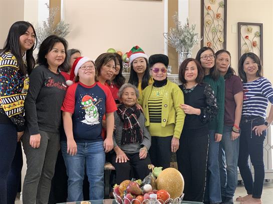 Friends are joyfully posed together in holiday attire, celebrating in a cozy home setting.