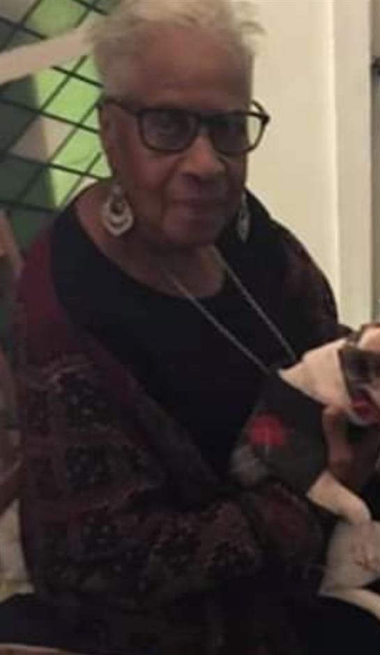 An elderly woman enjoys quality time with her small dog in a bright indoor space decorated with art.