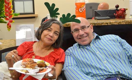 Two people enjoy a festive meal, relaxing in playful holiday headbands.