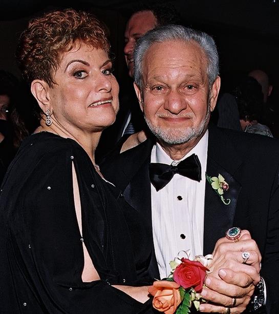 A well-dressed couple enjoys dancing together at a formal gathering, showcasing their happiness.