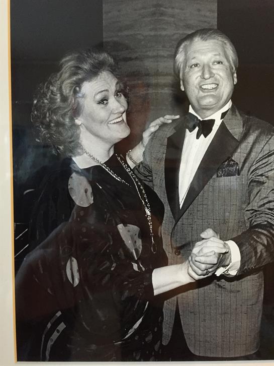 Two people are enjoying a dance, dressed elegantly for a glamorous evening event.