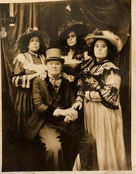 Four people in vintage attire pose for a portrait, highlighting their outfits and expressions.