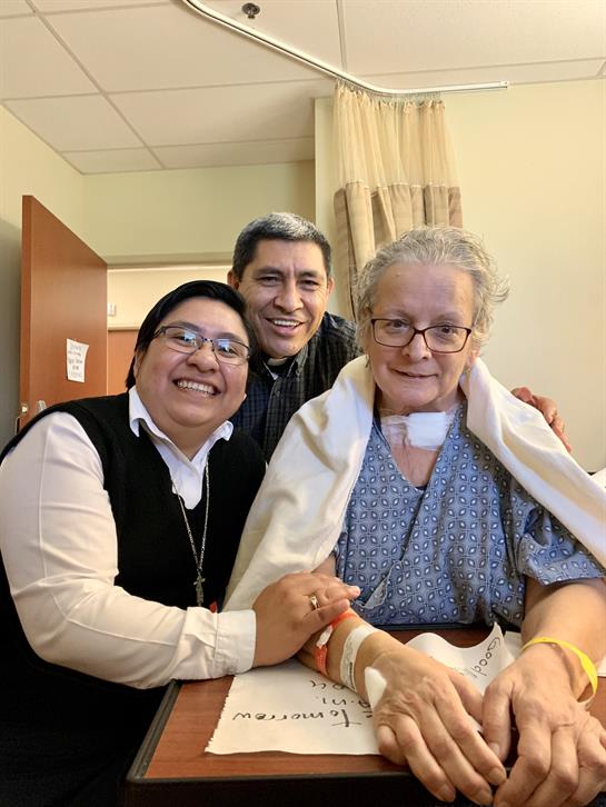 Cheerful moment among two sisters and a patient in a hospital room during the afternoon.