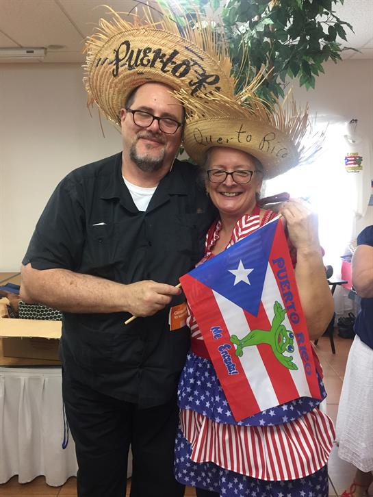 Two attendees display Puerto Rican pride in festive hats at a lively community event.