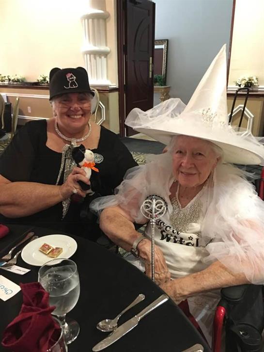 Two joyful women celebrate at a vibrant event, showing off their whimsical costumes and accessories.