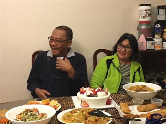 Two friends enjoy a joyful evening together around a table filled with diverse dishes.