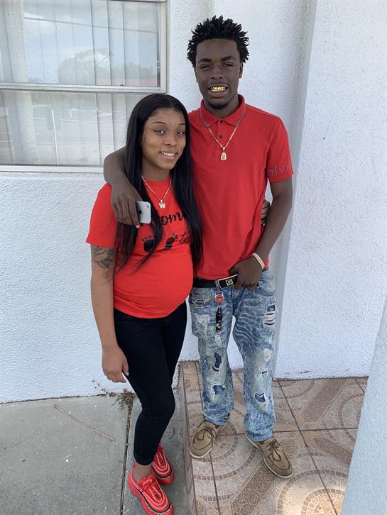A young couple stands happily outside a building, smiling and enjoying their time together.