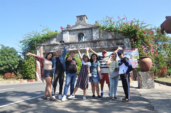 A cheerful group of friends poses in front of a historic building under clear blue skies.