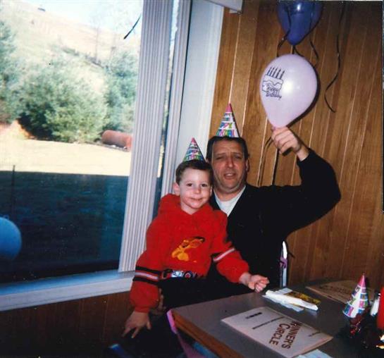A happy father and son in party hats, surrounded by colorful balloons and decorations.