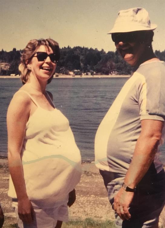 Enjoying a lighthearted moment at the beach, a couple shares smiles while expecting.