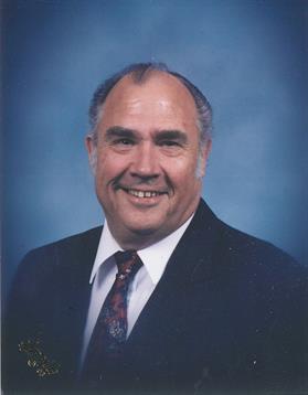 A friendly senior man shows his pleasant demeanor while dressed in a suit with a tie.