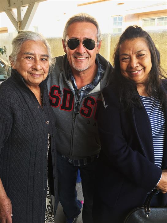 Three people share a happy moment outdoors, enjoying the warmth of the sun and each other’s company.