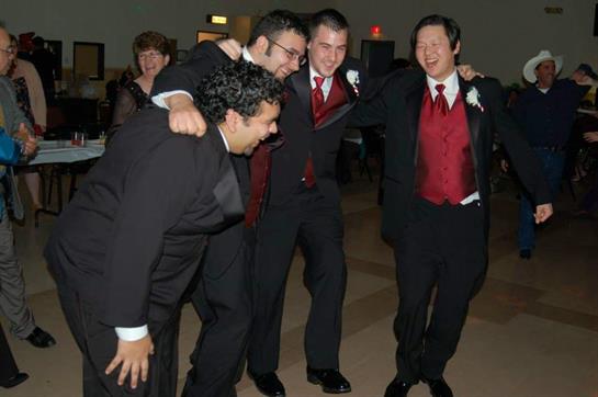 Four friends dance together at a formal event, laughing and bonding in elegant attire.