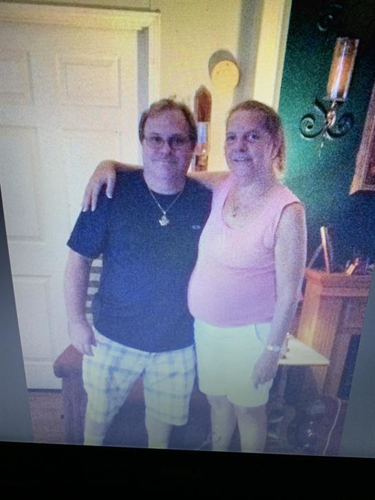 Two friends smile warmly together in a cozy indoor setting.