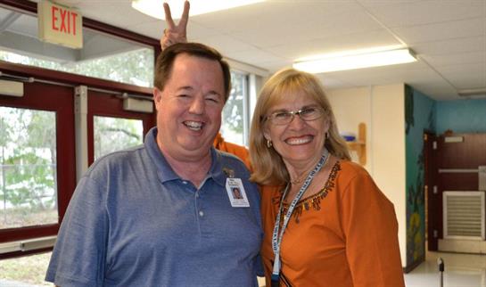 Two friends share laughter and joy in a bright classroom filled with warmth and camaraderie.