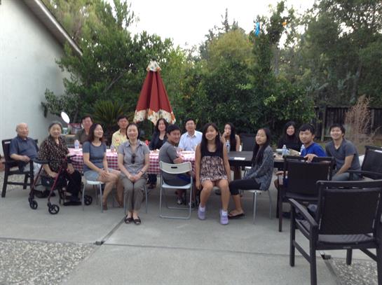 Group of people sitting around tables, sharing laughter and conversations in a vibrant garden area.