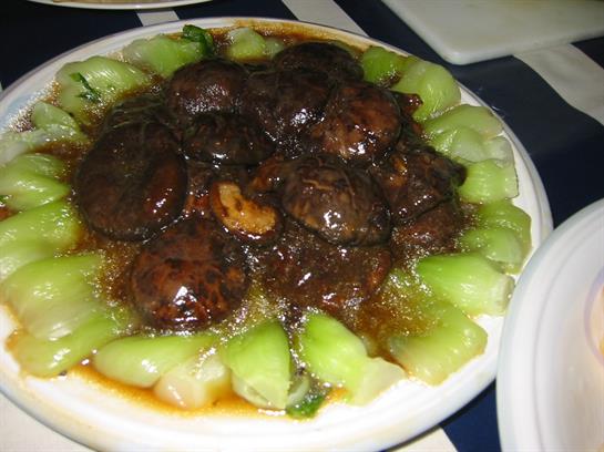 Juicy snails cooked in a rich sauce are served alongside fresh melon slices for a unique dish.