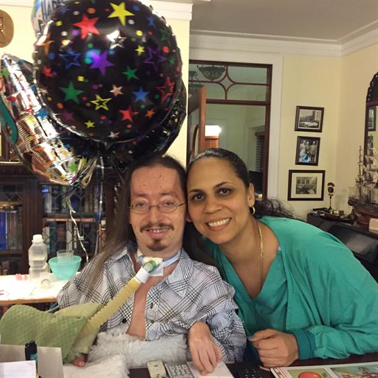 A person with disabilities celebrates a birthday surrounded by loved ones and decorations.