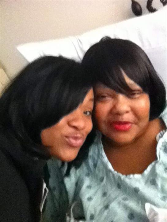 Two friends smile joyfully while spending quality time together in a hospital room.