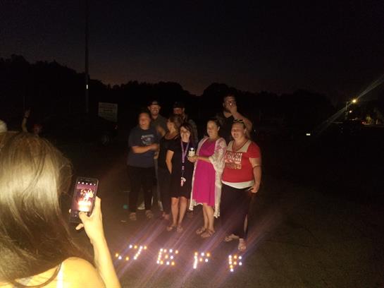 Friends and family gather outdoors at night, holding candles for a cozy vibe.