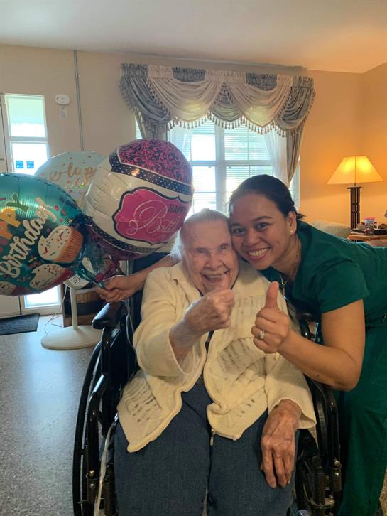 Residents and staff share laughter and joy during a birthday celebration filled with balloons.