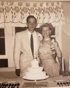 Couple celebrates their special day at a decorated table with a wedding cake in a cozy home.