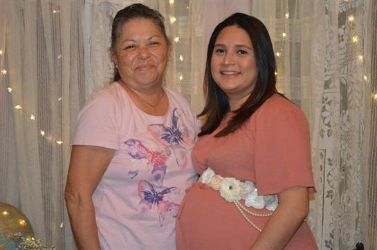 Two women stand close, smiling joyfully while celebrating an important family milestone.