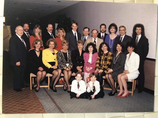 A diverse group of people gathers in formal outfits to celebrate during a special event.