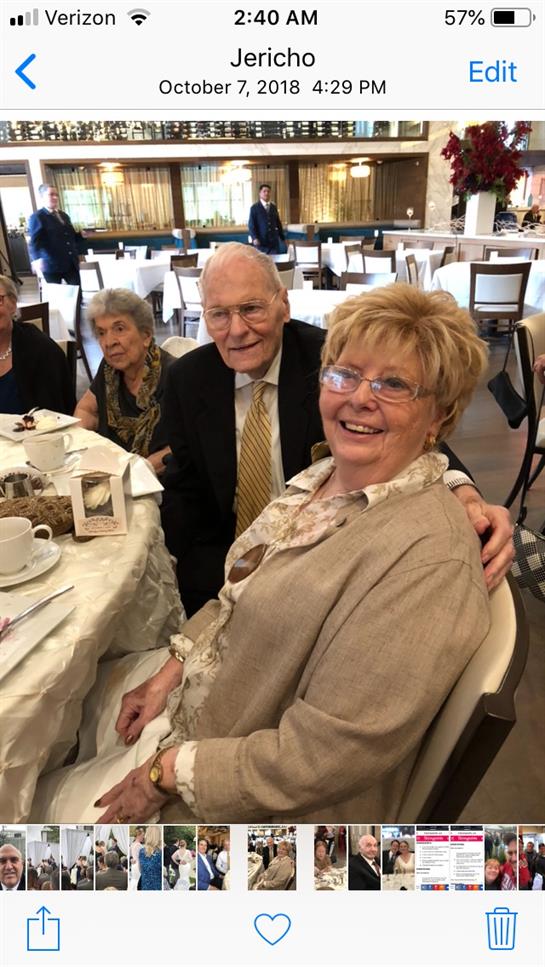A couple smiles happily at a table with friends during a gathering in a banquet hall.