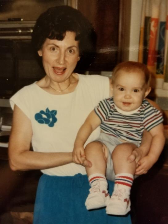 Loving grandmother joyfully holds her baby grandchild in a cozy living room.