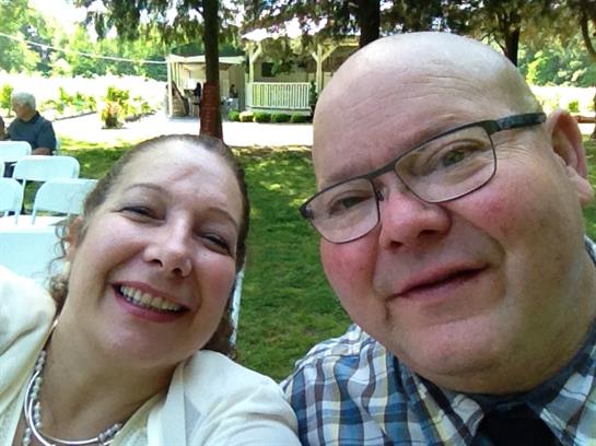 Couple smiles brightly as they capture a joyful moment in a beautiful park setting.