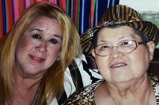 Two women share a warm smile in a colorful environment, capturing a cherished memory together.