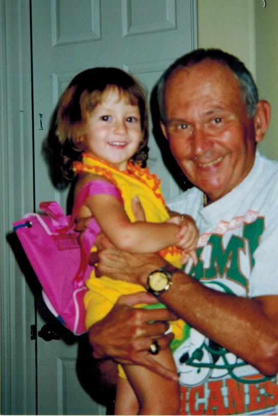 A loving grandfather embraces his cheerful granddaughter, both beaming with happiness in their home.