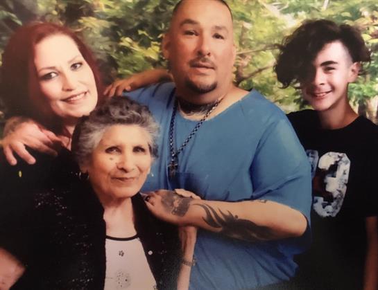 Four family members smile warmly, enjoying a moment of connection outdoors surrounded by greenery.