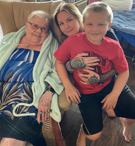 Grandmother smiles beside her daughter and grandson, enjoying quality family time indoors together.